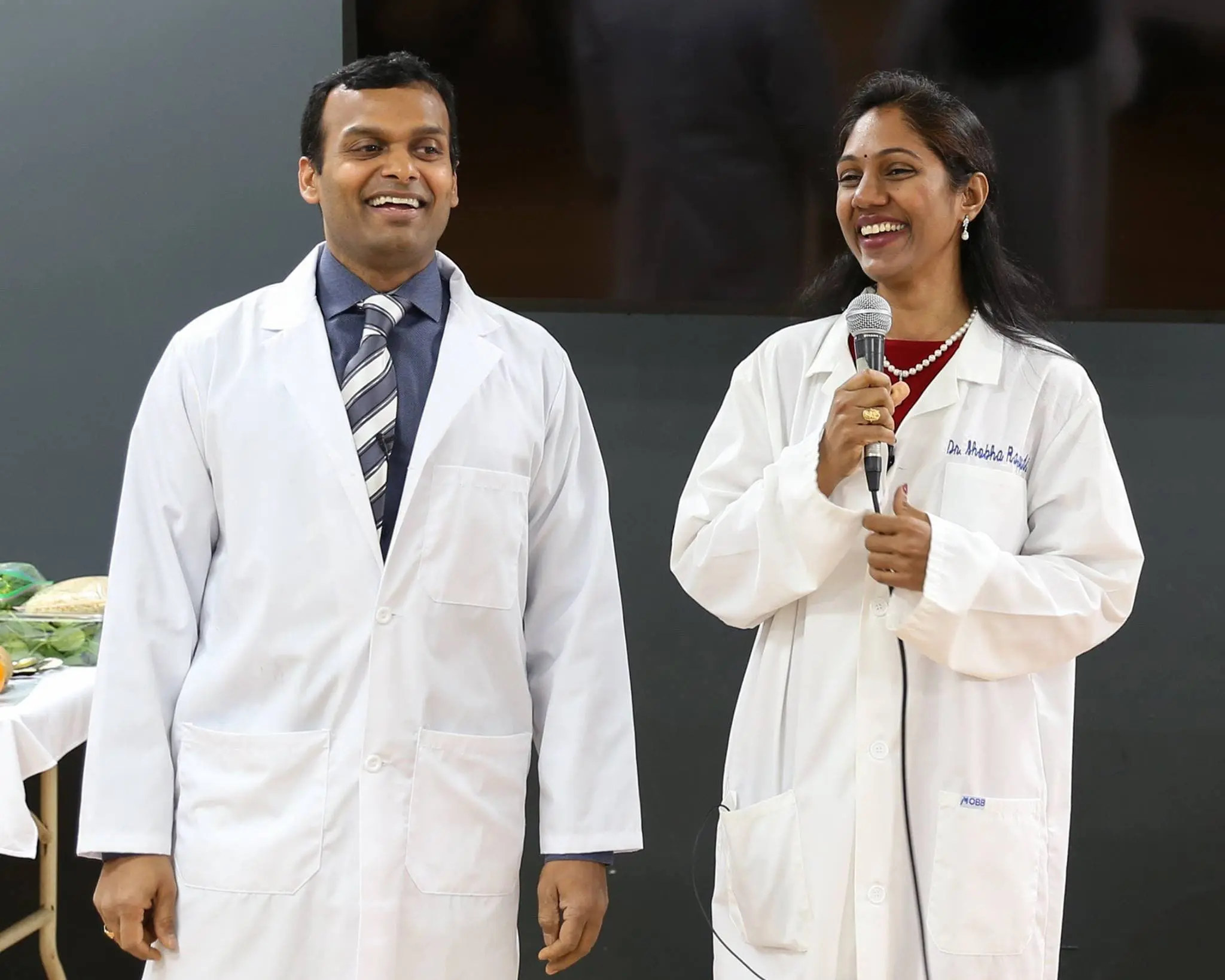 Two doctors smiling during a presentation.
