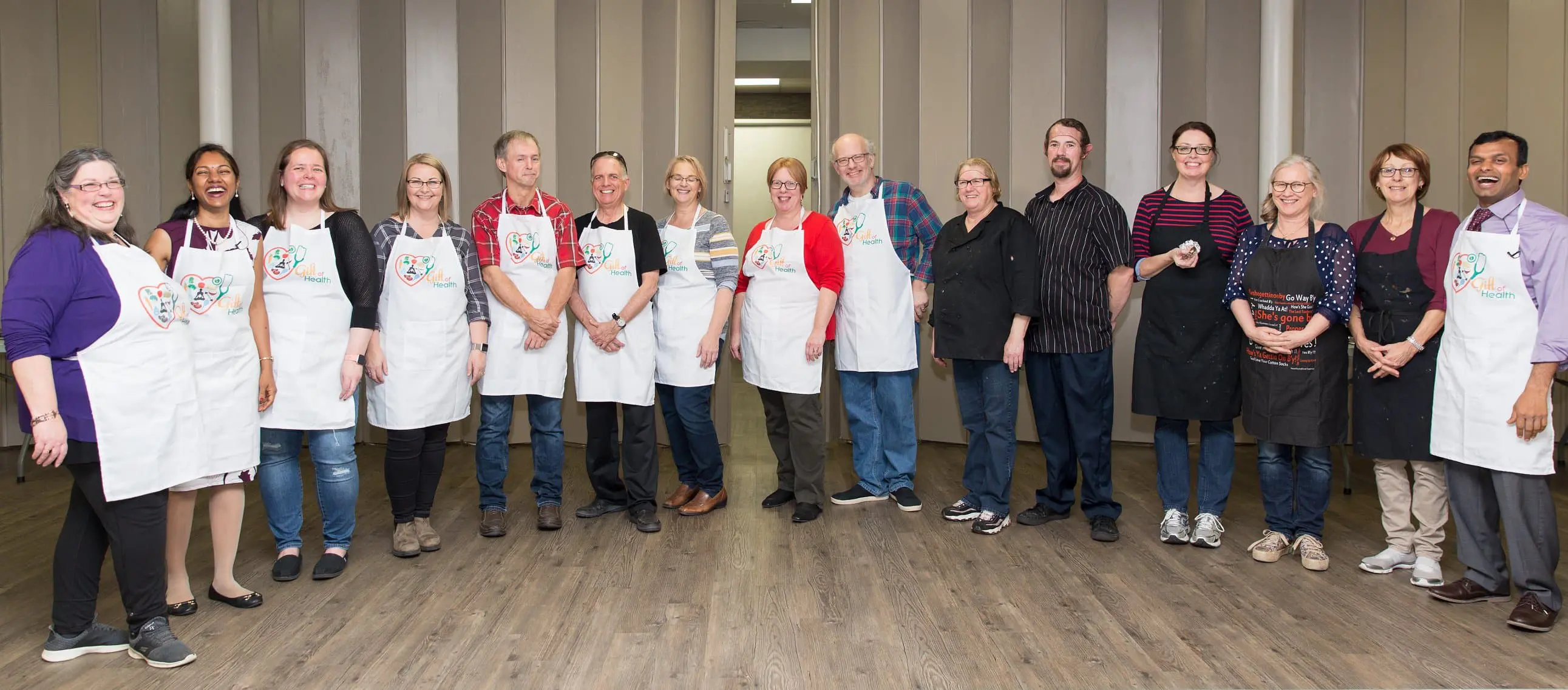 Group of people wearing aprons, standing indoors.