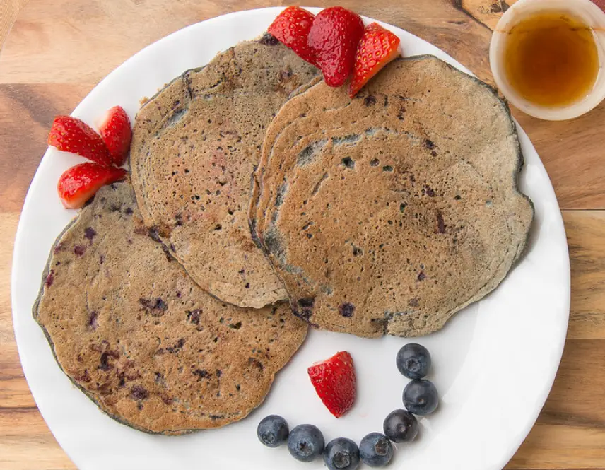 Pancakes with strawberries, blueberries, and syrup.