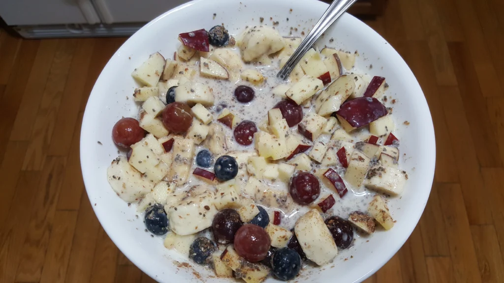 Bowl of fruit with milk and spoon.