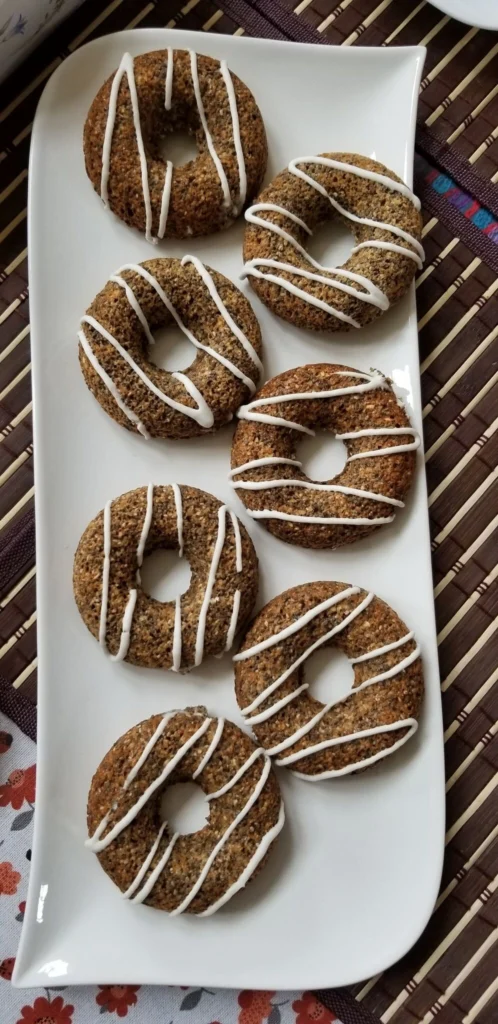 Seven donuts with white icing on plate.
