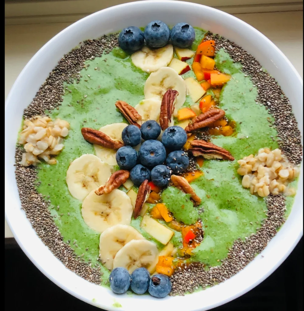 Green smoothie bowl with fruits and nuts.