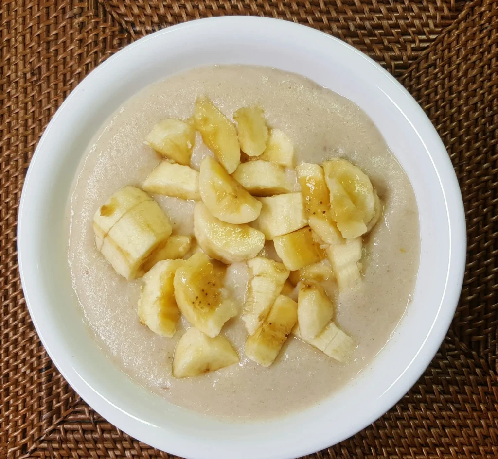 Bowl of porridge topped with sliced bananas.