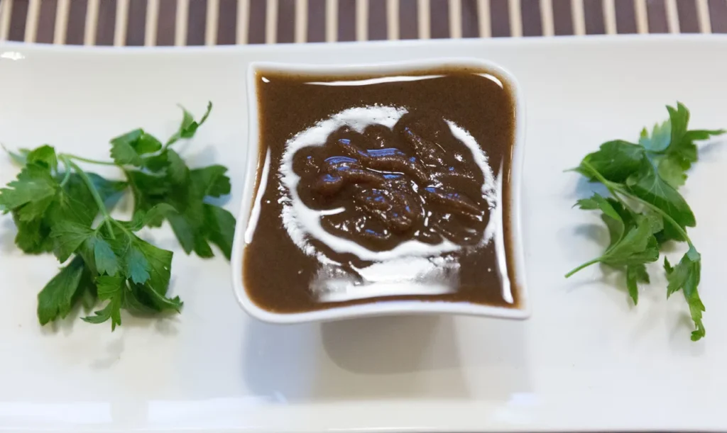 Brown sauce with parsley garnish on plate.