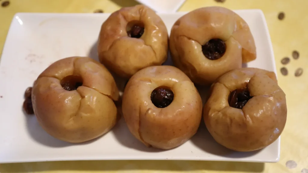 Baked apples with raisins on white plate.