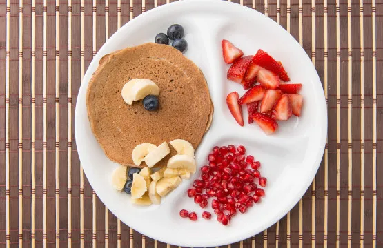 Pancake with fruit on a divided plate.
