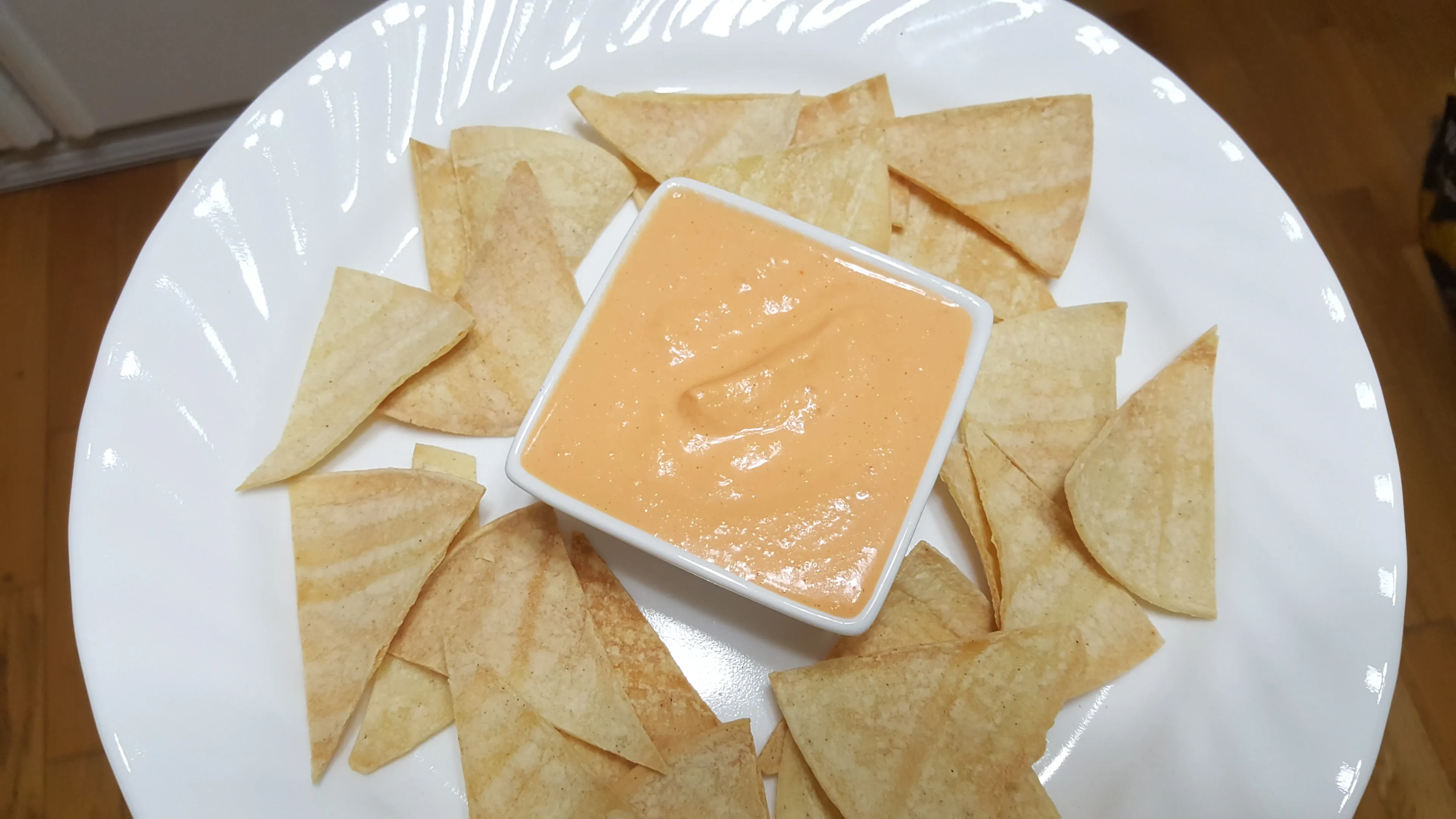 Tortilla chips with cheese dip on plate.
