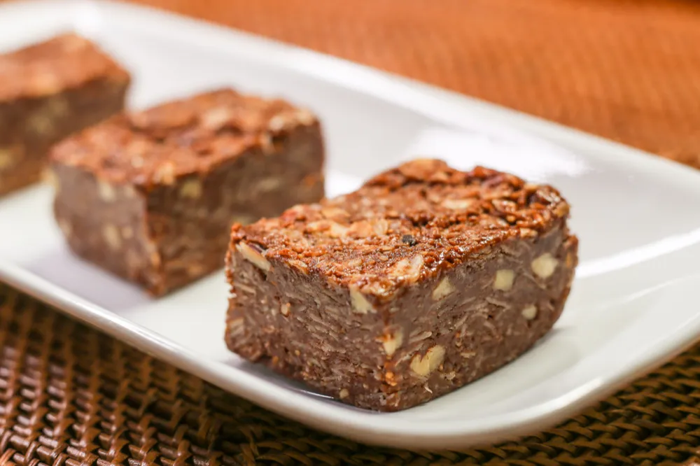Chocolate squares with nuts on white plate.