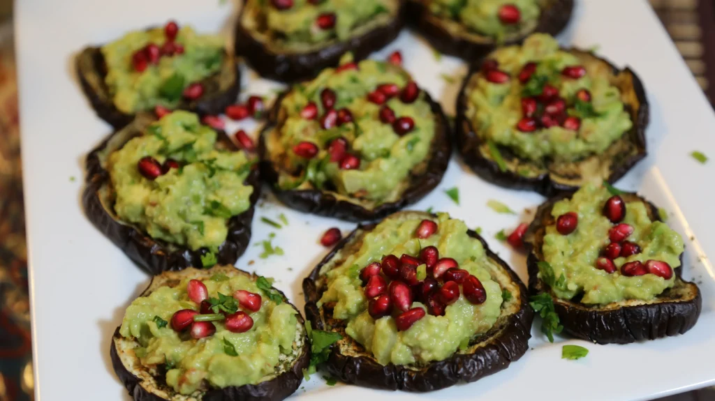 Eggplant slices topped with guacamole and pomegranate.