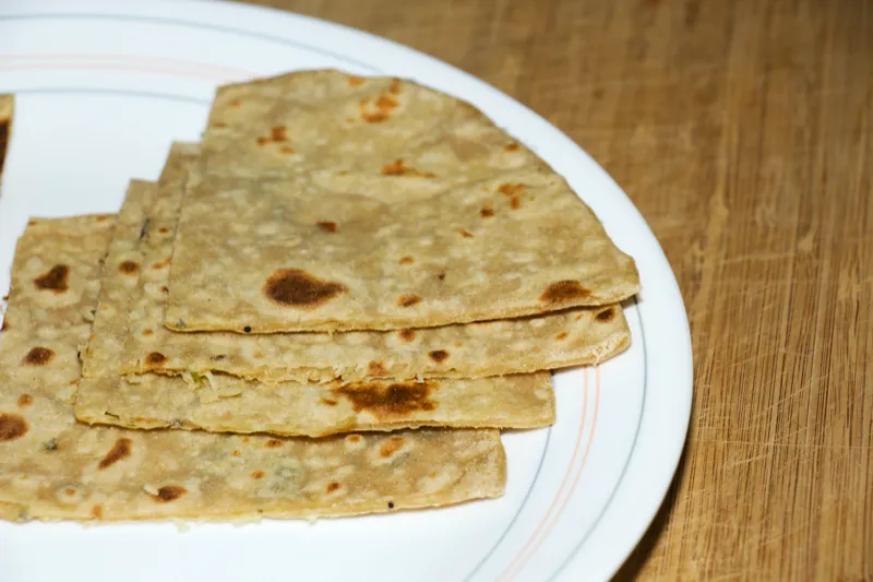 Stack of flatbreads on white plate.