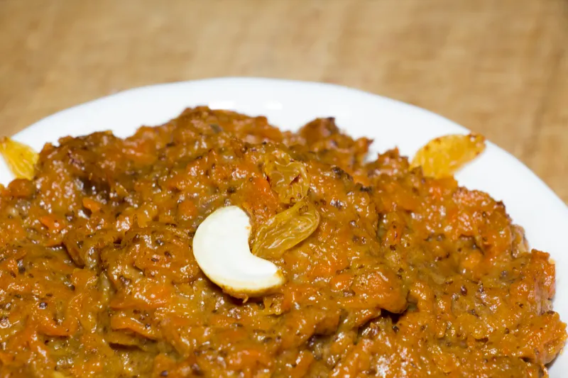 Carrot halwa garnished with cashew and raisins.