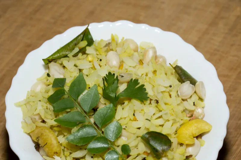 Poha garnished with curry leaves and nuts.