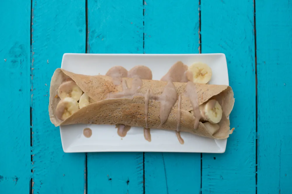 Crepe with banana slices on blue table.