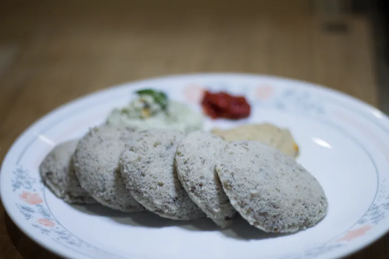 Ragi idlis with chutneys on a plate.