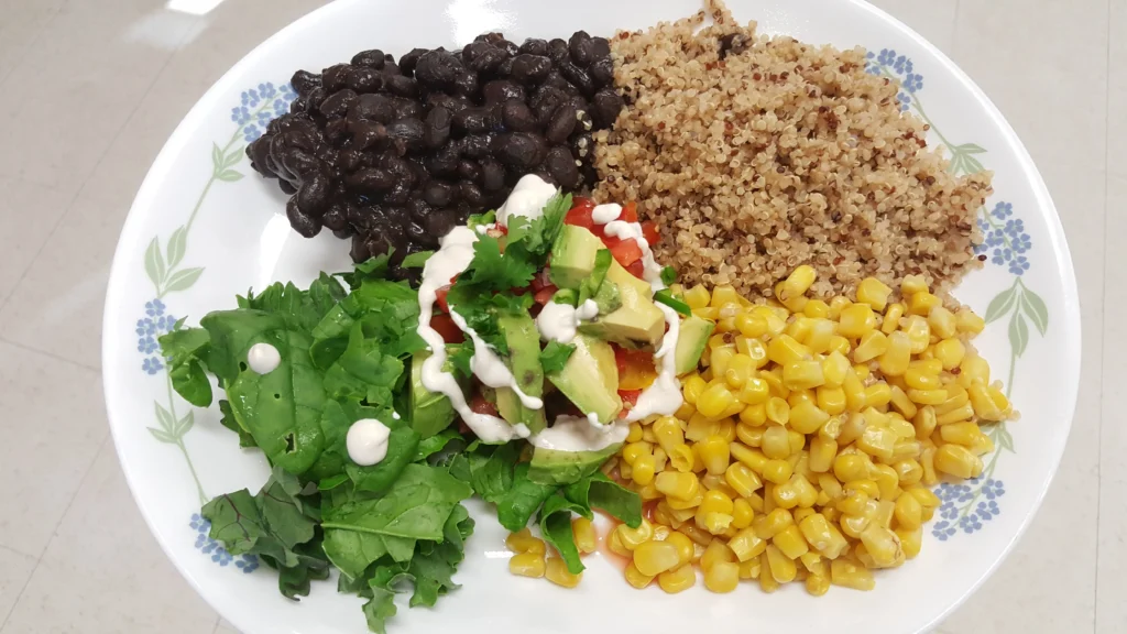 Colorful vegetarian plate with beans, quinoa, corn.