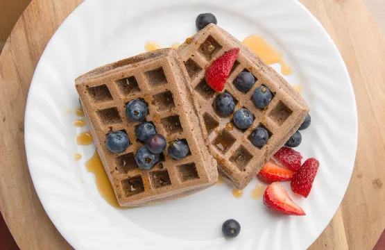 Waffles with blueberries and strawberries on plate.