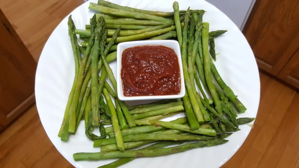 Asparagus with dip on a white plate.