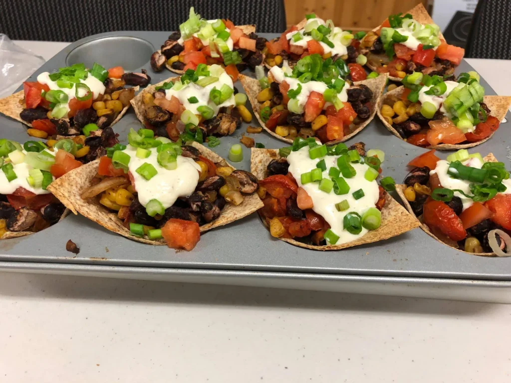 Taco cups with toppings in muffin tray.