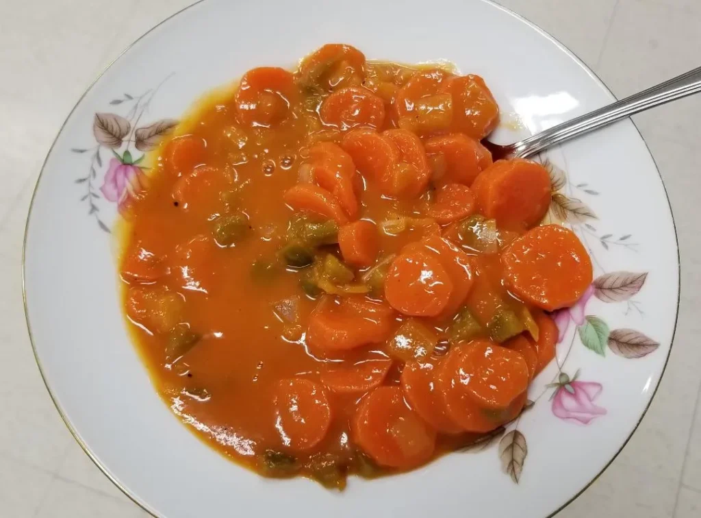 Carrot dish in floral-patterned bowl with spoon.