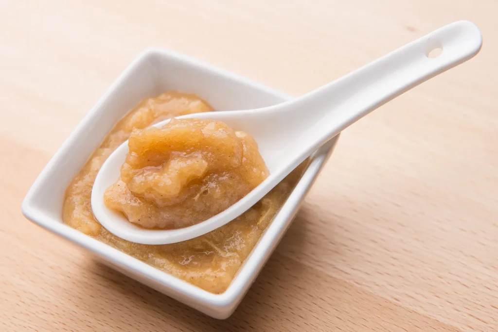 Applesauce in ceramic dish with spoon.