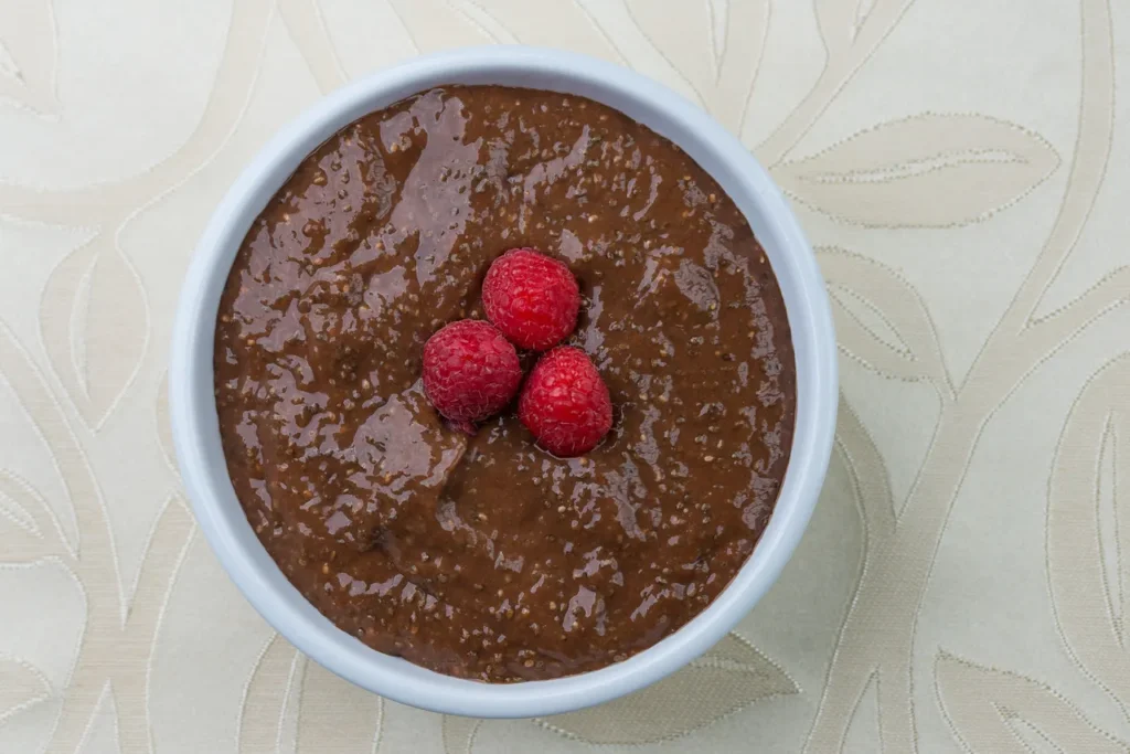 Chocolate pudding topped with three raspberries.