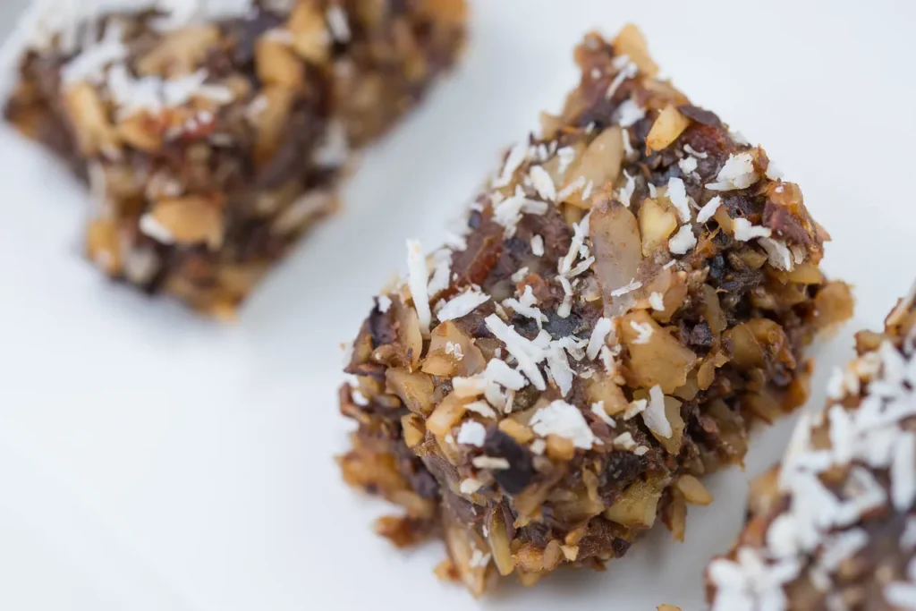 Nutty dessert bars topped with coconut flakes.