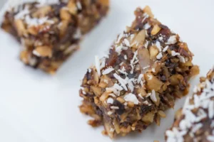 Nutty dessert bars topped with coconut flakes.