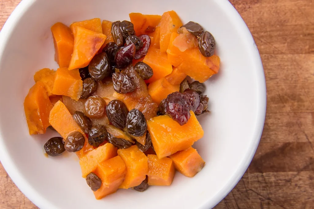 Diced sweet potatoes with raisins in bowl.