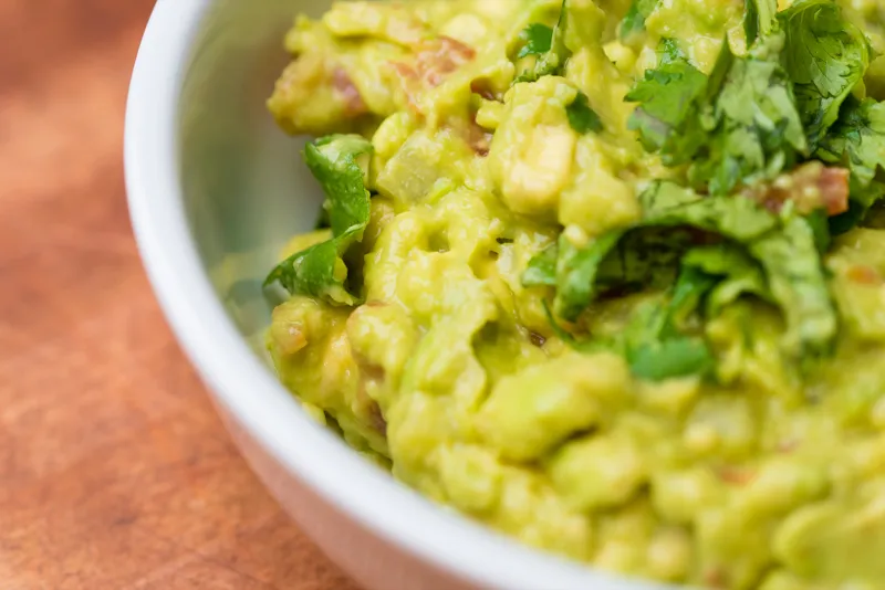 Bowl of guacamole with fresh cilantro.