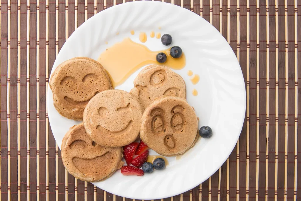 Smiley pancakes with blueberries and syrup.