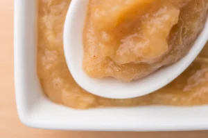 Applesauce in white dish with spoon.